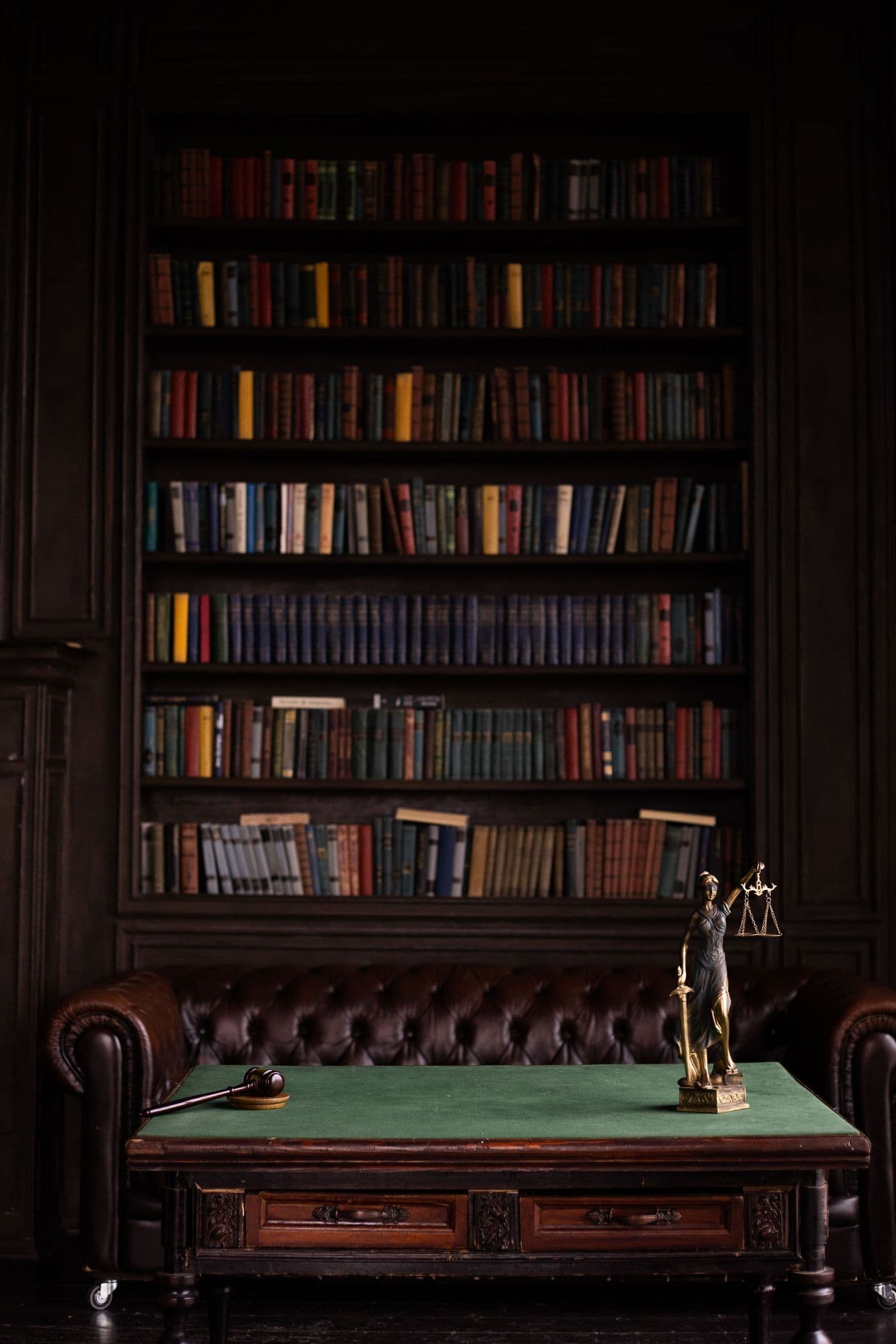Bureau d'un cabinet d'avocats : bibliothèque, fauteuil en cuir et statue de la Justice