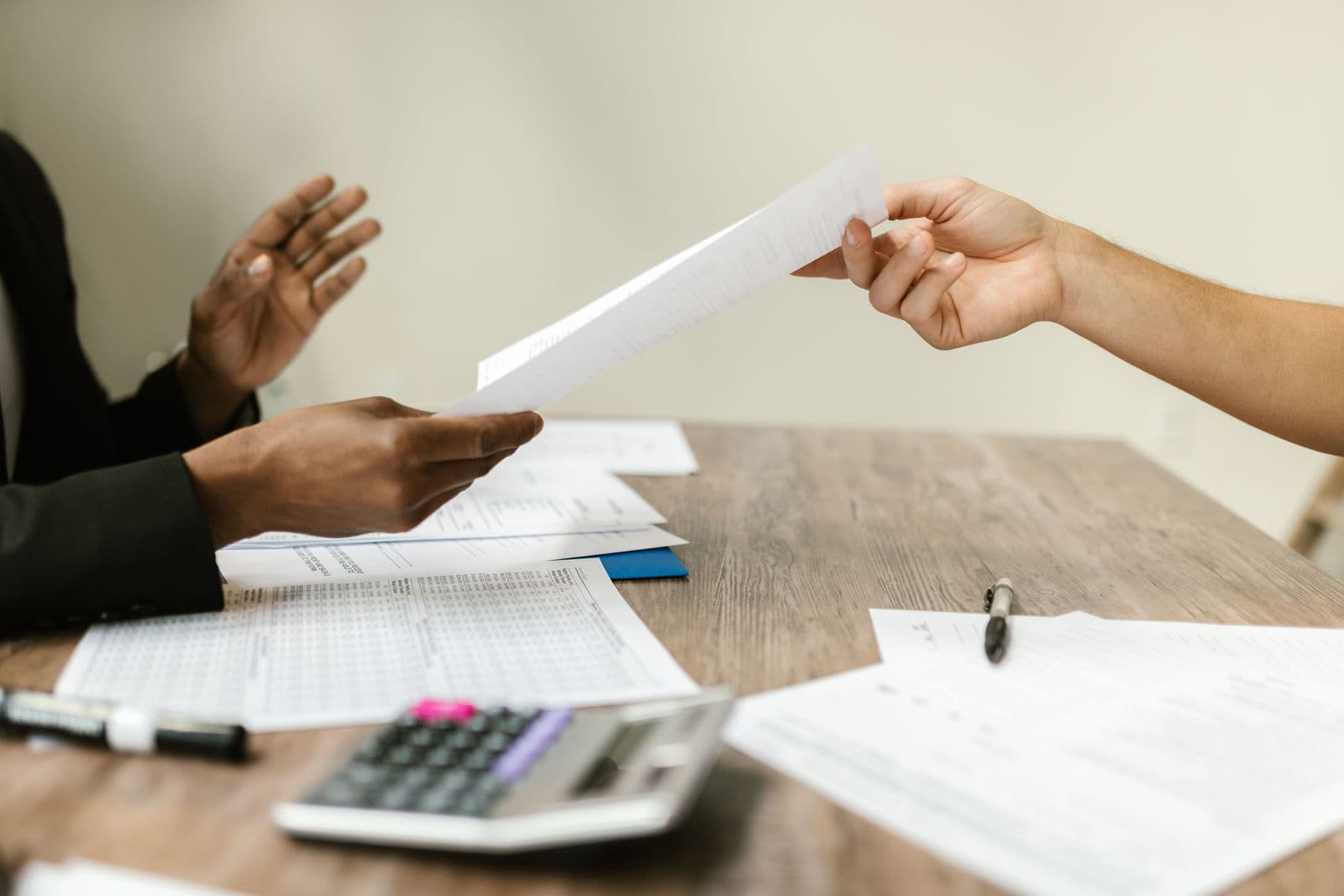 Pièces comptables échangées sur un bureau, calculatrice à portée de main