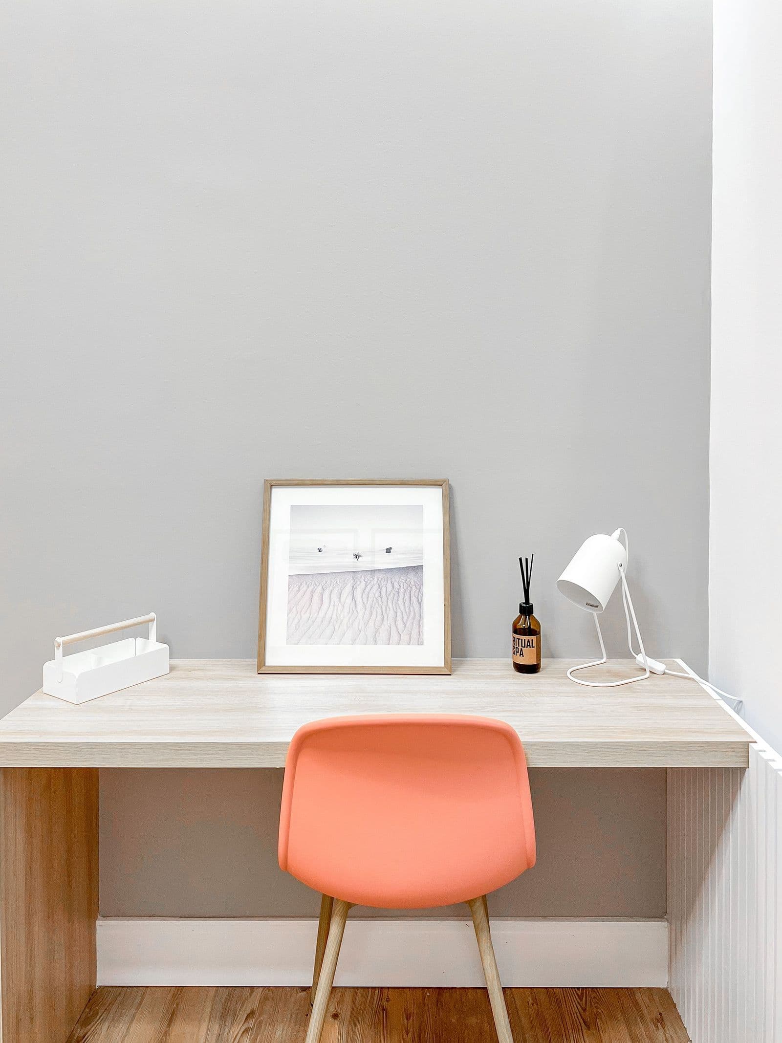Poste de travail sobre : bureau en bois, chaise orange et lampe